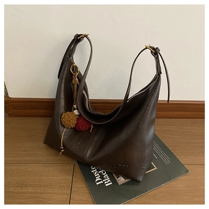 Detailed view of dark brown tote bag featuring textured leather and colorful plush charms