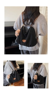 Detail of black tote bag with brown leather straps and cute plush bear charm accessory