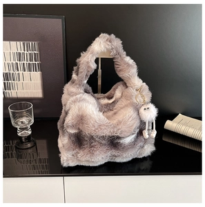 Detailed close-up of a grey plush handbag featuring a fun white monster charm