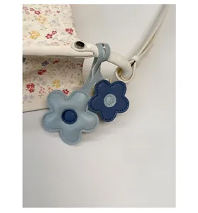 Detail view of floral pattern tote bag featuring cute blue leather flower pendants