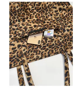 Détail de la poche avant d'un sac cabas léopard contenant un téléphone et des mouchoirs