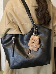 Klassische schwarze Leder-Tote-Bag mit Hundeanhänger, präsentiert an Trenchcoat-Model