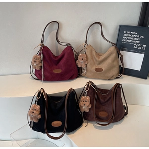 Detailed view of four suede tote bags in various colors with cute plush bear charms