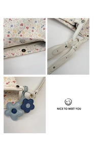 Detail of floral tote bag featuring magnetic closure, metal rivets, and blue flower charms