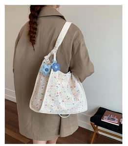 Detailed close-up of a floral tote bag with blue flower charms and wide white straps