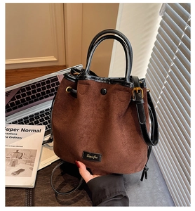 Détail du sac seau en daim marron avec poignée en cuir noir et finitions dorées chic
