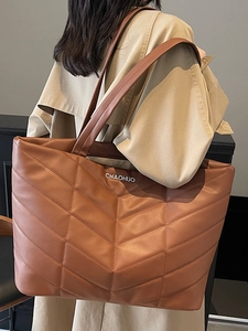 Minimalist brown quilted tote bag with wide shoulder strap shown on a model for daily use