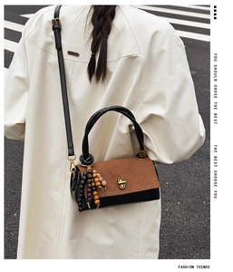 Detailed view of vintage crossbody bag with wood bead charm on a white coat model