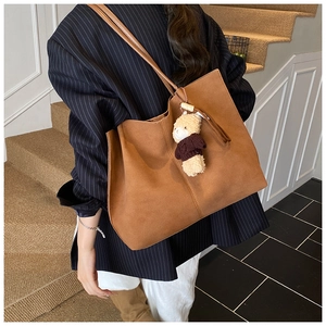 Braune Shopper-Tasche aus Wildleder mit Bärenanhänger, präsentiert von einem Model