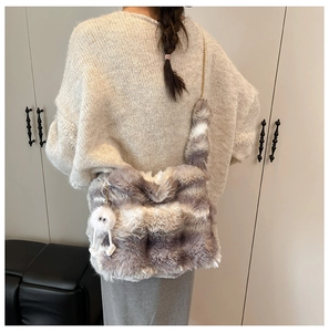 Close-up of a striped faux fur handbag with a plush ball charm and gold chain strap
