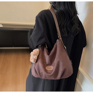 Brown suede tote bag with Banatu logo and plush bear charm shown on model's shoulder