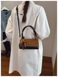 Detail view of contrast textures on a minimalist brown suede and black leather shoulder bag
