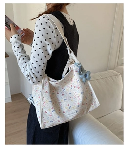 Close-up of floral tote bag with a blue flower charm and adjustable white shoulder strap