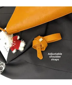 Detail view of ginger yellow lychee leather bag with dual straps and bear pendant accessory