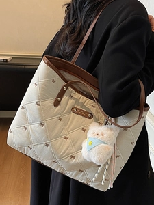 Gesteppte Tragetasche mit Schleifenstickerei und Bärenanhänger an Modell in schwarzem Blazer