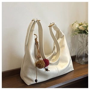 Detail of off-white Hobo shoulder bag with matte leather texture and plush ball charms