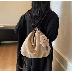 Detail of khaki hobo bag with adjustable brown strap and cute plush bear charm