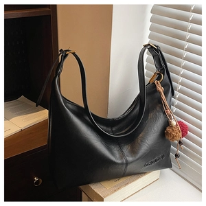 Detail of black leather hobo bag with vintage gold hardware and a beaded charm