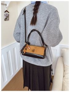 Detail of retro flap bag with brown suede patchwork, gold lock, and wooden bead charm