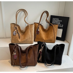 Detail of four suede tote bags in khaki and brown with teddy bear charms on stairs