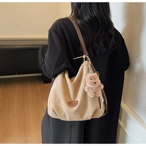 Detailed close-up of khaki suede tote bag with brown leather strap and bear charm