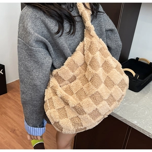 Close-up of a large beige checkered plush hobo bag worn as a crossbody on a model