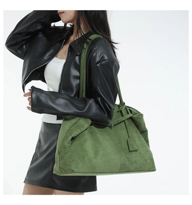 Forest green suede bucket bag with long shoulder strap shown in a professional model shot