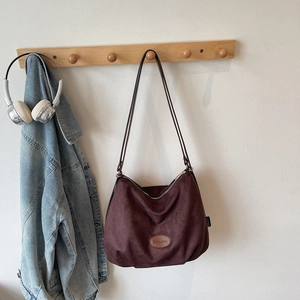 Close-up of vintage dark wine red suede tote bag with Banatu logo patch on wood hook
