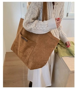 Détail du cabas en daim marron caramel avec étiquette logo en cuir et large bandoulière