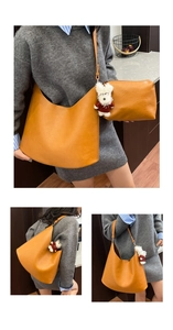 Detail of ginger yellow tote bag set with textured leather and puppy plush charm