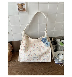 Detailed macro view of floral canvas tote bag featuring leather straps and flower charms