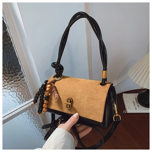 Detail of retro leather handbag featuring brown suede flap and golden metal swivel lock