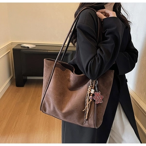 Close-up of deep coffee suede tote bag featuring a cute bear charm and colorful tassel