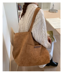 Détail du sac fourre-tout en daim marron avec grande poche avant et logo élégant