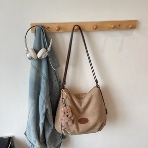 Detail view of light brown suede tote bag with cute puppy plush charm and leather strap