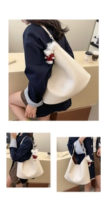 Large beige hobo shoulder bag with a cute plush rabbit pendant in a minimalist interior