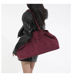 Détail d'un grand sac cabas en velours bordeaux porté avec une veste en cuir noir