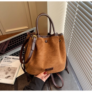 Détail du sac seau en daim caramel avec fermeture à cordon et poignées marron foncé