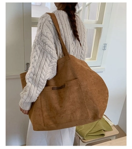 Détail d'un grand sac cabas en daim marron avec poche frontale et étiquette logo