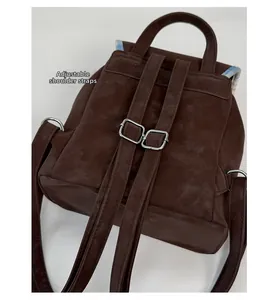 Detail view of adjustable shoulder straps on a vintage brown suede-textured backpack