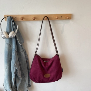 Close-up of burgundy suede tote bag with brown leather straps and vintage finish