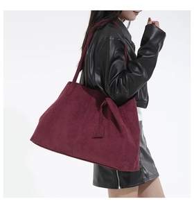 Mannequin portant un grand sac cabas bordeaux en daim avec une veste en cuir minimaliste