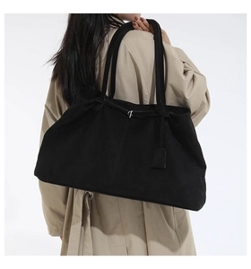Vue détaillée d'un grand sac fourre-tout en daim noir avec doubles bretelles et pendentif