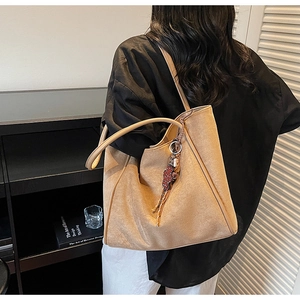 Detail of camel suede tote bag with cute bear charm and adjustable shoulder strap