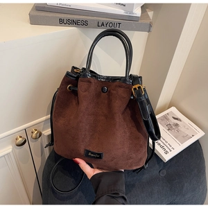 Détail du sac seau en daim marron avec finitions en cuir noir et boucles dorées