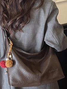 Fashionable dark brown leather tote bag with soft texture and stylish pompom charm