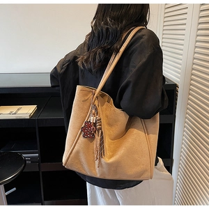 Detail of light brown faux suede tote bag with red polka dot bear charm and tassel