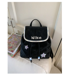Detail of velvet backpack featuring blue and yellow plaid star patches and drawstring closure