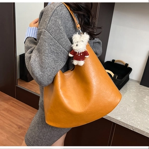 Grand sac fourre-tout orange en cuir avec un pendentif ours en peluche blanc sur la sangle