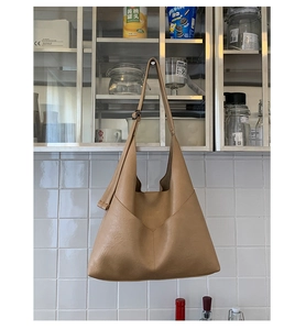 Detail of camel brown faux leather tote bag with V-shaped stitching on kitchen cabinet